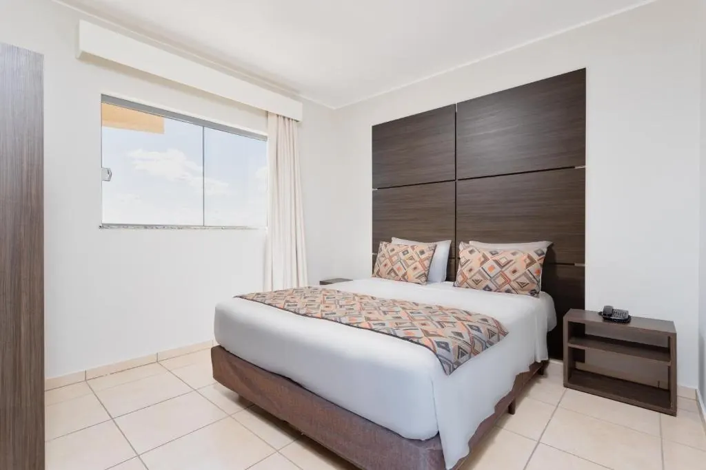 Quarto com cama de casal e cabeceira de madeira
