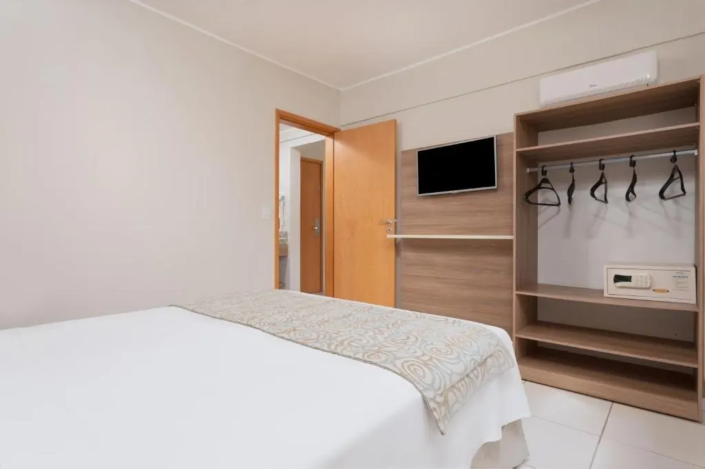 Quarto com armário aberto e TV